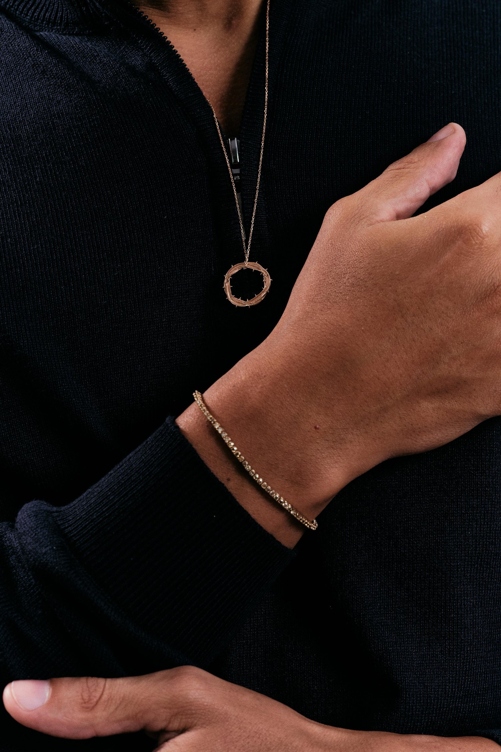Pingente de aro e pulseira de ouro sobre suéter azul-marinho