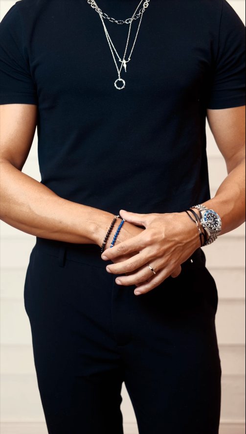 Camiseta preta com colares de prata, pulseiras e relógio